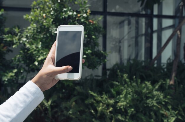 Mujer con smartphone para tomar fotos o enviar mensajes de texto afuera