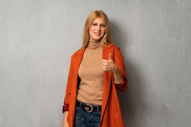 Mujer sobre fondo de textura dando un pulgar hacia arriba gesto con ambas manos y sonriendo