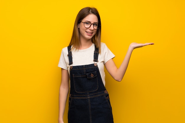 Mujer sobre una pared amarilla con copyspace imaginario en la palma para insertar un anuncio