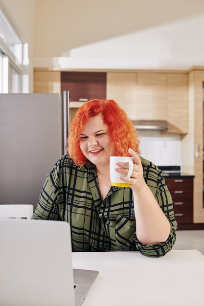 Mujer con sobrepeso bebiendo café por la mañana