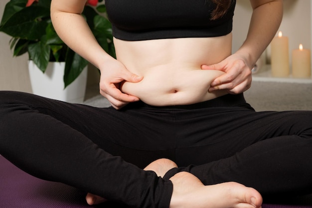 Una mujer con sobrepeso estaba haciendo yoga muestra el primer plano de la grasa del vientre