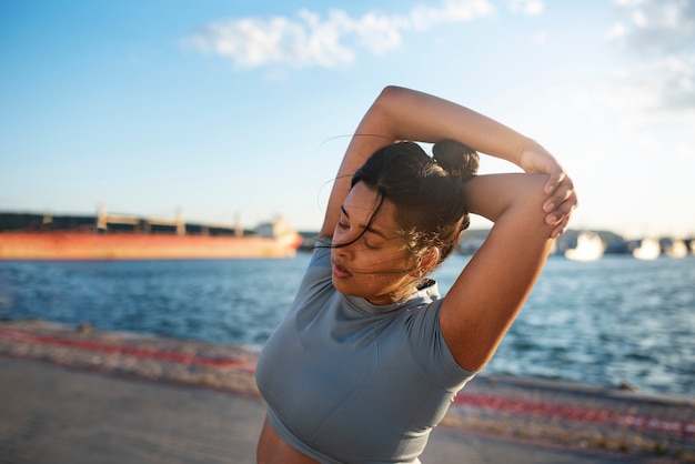 Mujer con sobrepeso haciendo ejercicio al aire libre junto al lago