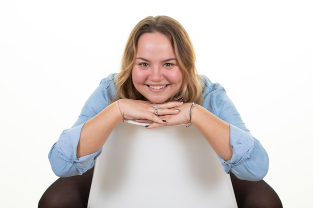 Mujer con sobrepeso sonriendo en la silla trasera sintiéndose feliz amistosa sentada satisfecha y despreocupada con las manos en la barbilla