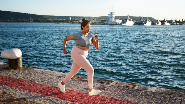 Foto mujer con sobrepeso trotando al aire libre junto al lago