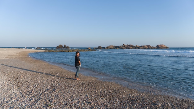 Mujer sola caminando disfrutando de la playa de belleza