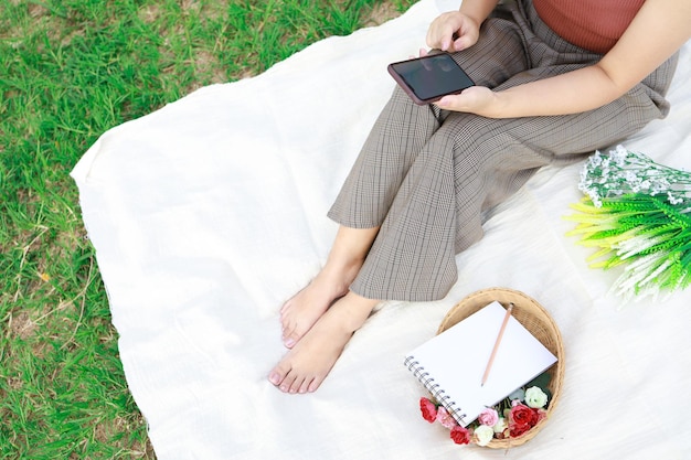 Mujer sola descansando en un picnic en el parque natural al aire libre en un día soleado disfrutando del verano y soñando