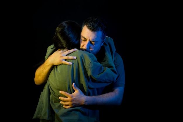 mujer soldado abraza a su marido por la guerra con uniforme militar en un fondo negro aislado