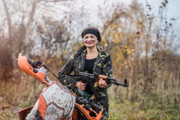 Mujer soldado con rifle sentado en motocicleta