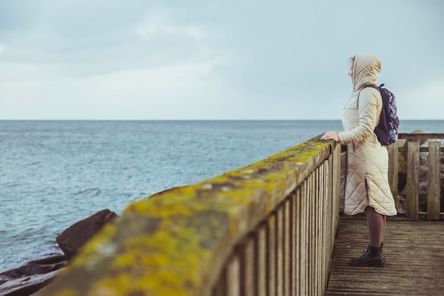 Mujer solitaria de pie en un muelle en Dinamarca