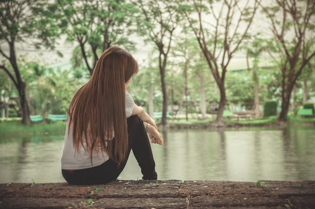 La mujer solitaria que se sienta en un de madera está sola