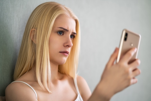 Mujer soltera preocupada mirando un teléfono móvil y esperando una llamada o mensaje