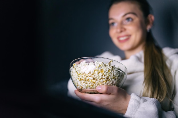 Mujer soltera viendo televisión en línea en la noche sentada en un sofá