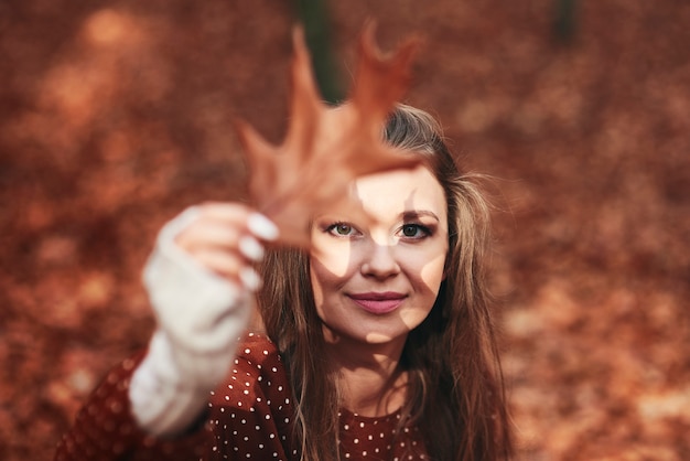 Mujer con sombra de hojas en la cara en el bosque de otoño