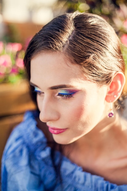 Mujer con sombras brillantes en su párpado y pestañas pintadas mira hacia abajo en un brillante día soleado de verano