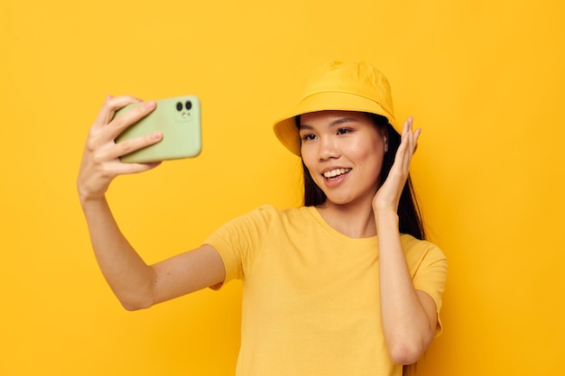 Mujer con un sombrero amarillo y una camiseta hablando por teléfono con una toma monocromática