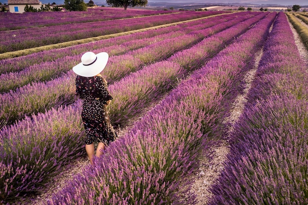 Mujer con sombrero blanco en campo de lavanda paisaje de atardecer de verano cerca de Valensole