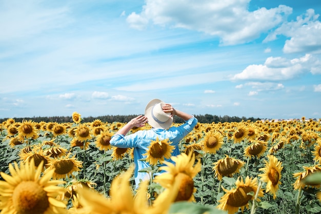 Mujer con sombrero en campo de girasoles disfrutando de la naturaleza