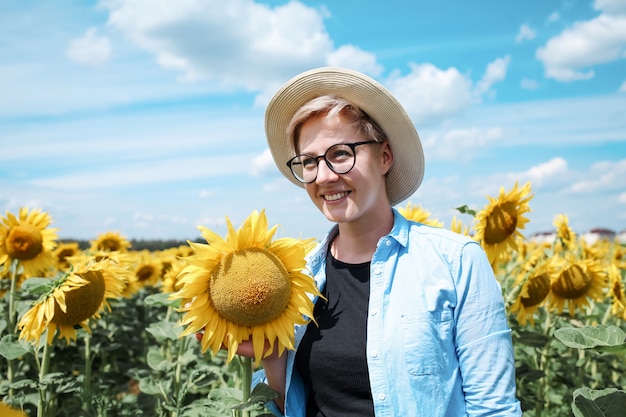 Mujer con sombrero en campo de girasoles disfrutando de la naturaleza