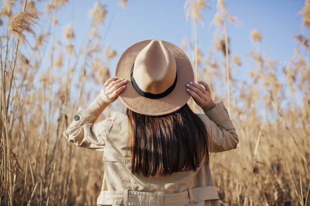 Mujer con sombrero contra el cielo azul y altas cañas secas