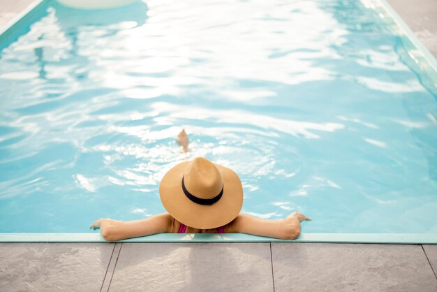 Foto mujer con sombrero descansa en la piscina