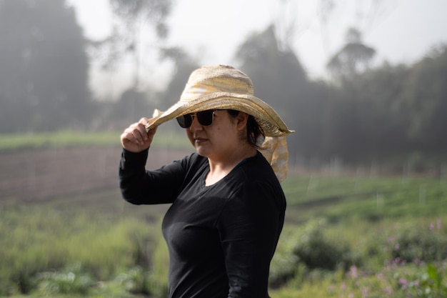 mujer con sombrero y gafas con fondo natural en un día soleado y nublado