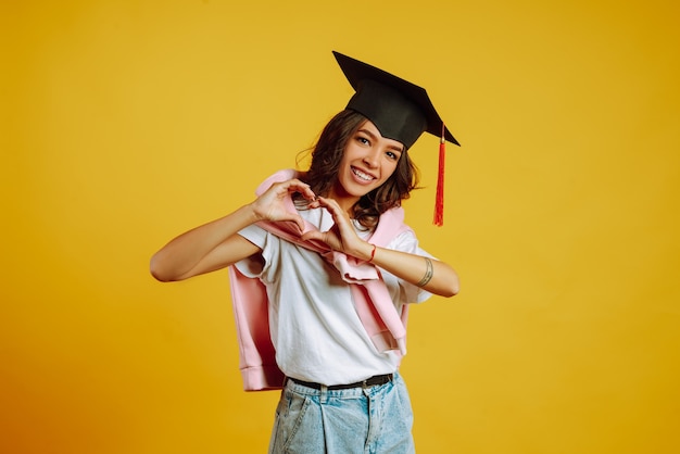 mujer con un sombrero de graduación haciendo signo de amor