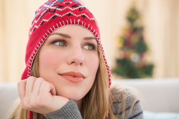 Mujer en sombrero de invierno pensando con la cabeza en la mano