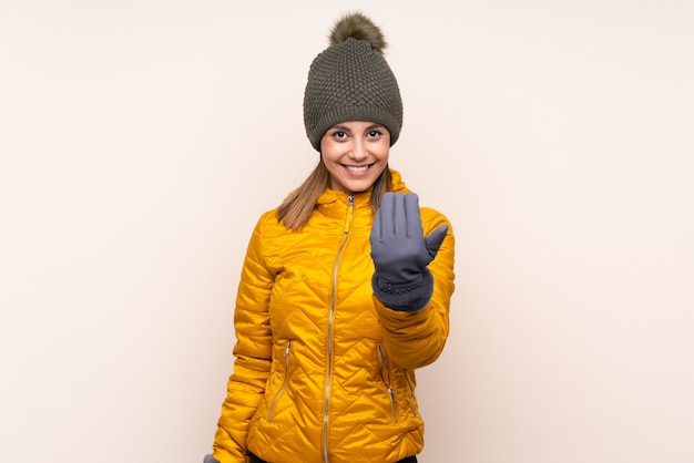 Mujer con sombrero de invierno sobre pared aislada invitando a venir