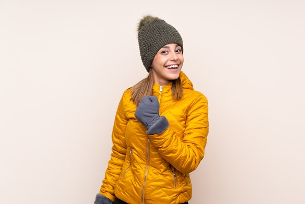 Mujer con sombrero de invierno sobre pared celebrando una victoria