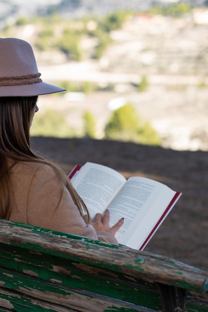 Mujer con sombrero leyendo en la naturaleza