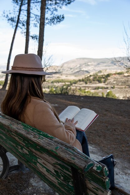 Mujer con sombrero leyendo en la naturaleza