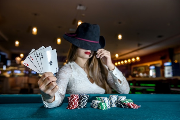 Mujer con sombrero con naipes y fichas de póquer en el casino