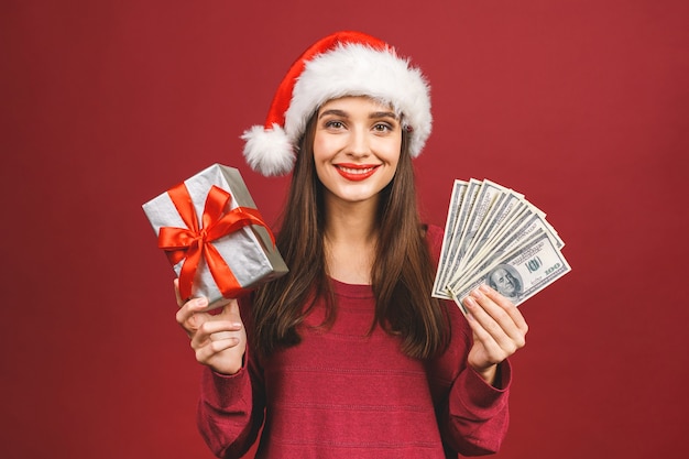 Mujer con sombrero de navidad con dinero y caja de regalo sorpresa