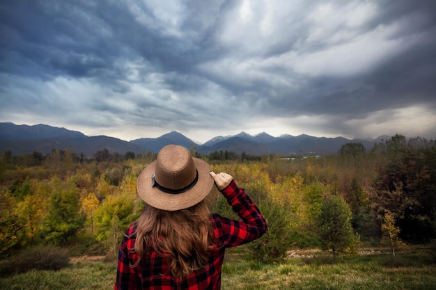 Mujer con sombrero en el paisaje de las montañas de otoño