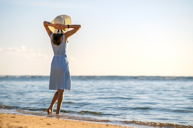 Mujer con sombrero de paja en una playa de arena