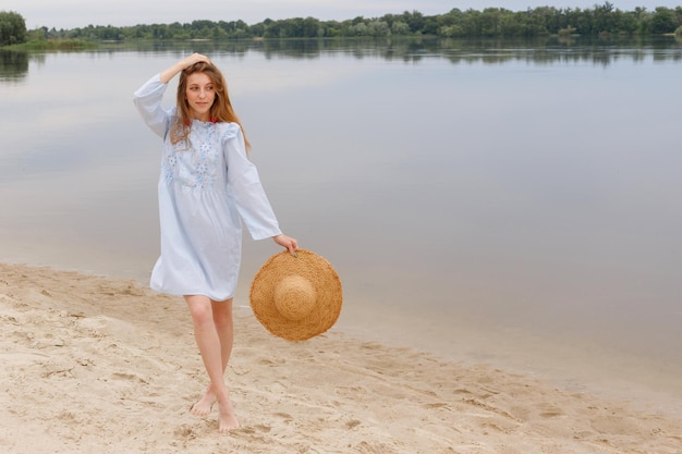 Mujer con sombrero de paja en la playa cerca del río en verano