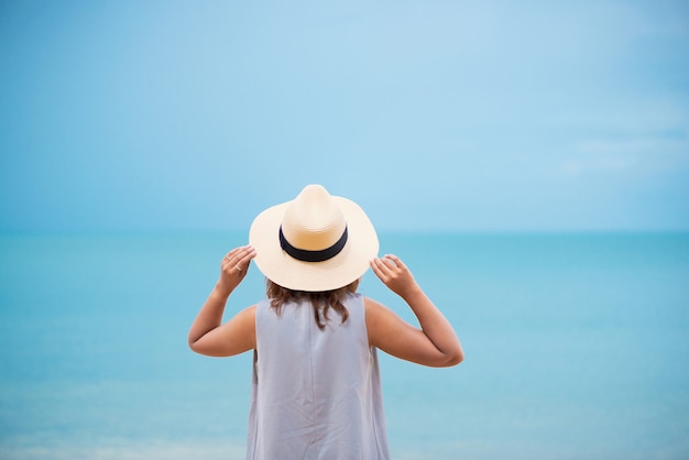 Mujer con el sombrero de paja que se relaja en la playa.