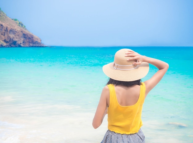 Mujer con sombrero de pie en la imagen borrosa de mar azul