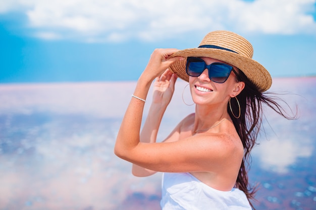 Mujer con sombrero a pie en un lago de sal rosa en un día soleado de verano.