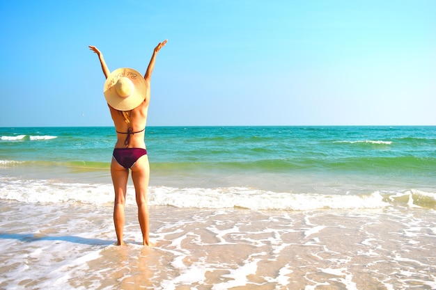 Mujer con sombrero en la playa Chica en traje de baño en el océano Vacaciones de verano tropical