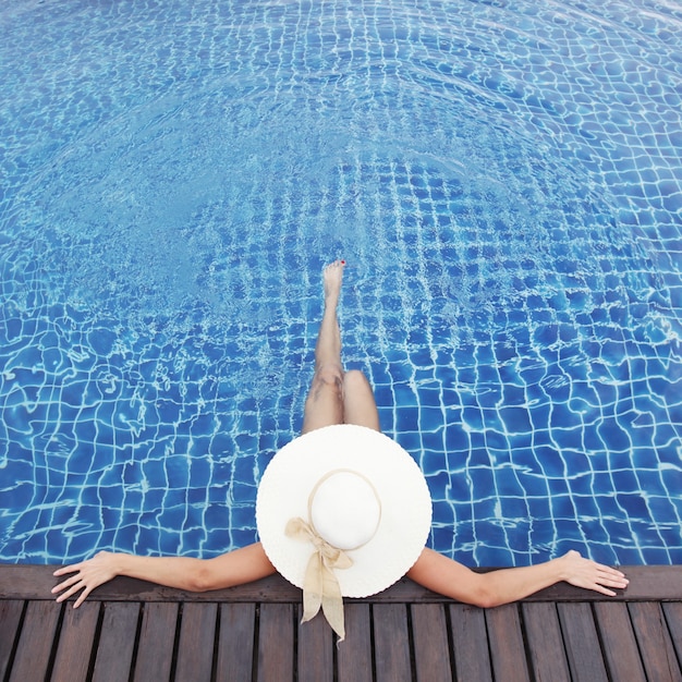 Mujer con sombrero relajante en la piscina