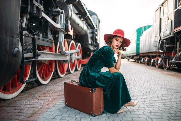 Mujer de sombrero rojo contra el tren de vapor vintage