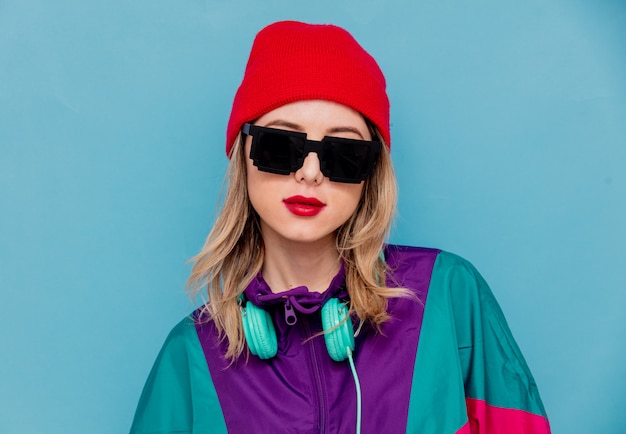 Mujer con sombrero rojo, gafas de sol y traje de los años 90 con auriculares.