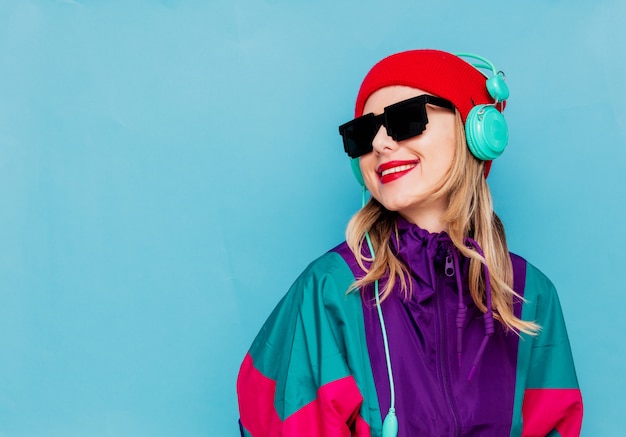 Mujer con sombrero rojo, gafas de sol y traje de los años 90 con auriculares.