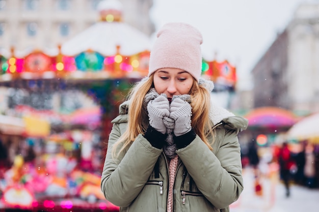 Una mujer con un sombrero rosa y una bufanda de lana tejida camina en el mercado de Navidad