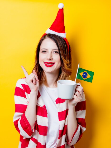 mujer con sombrero de santa claus con bandera de brasil y copa