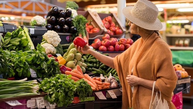 Foto mujer con sombrero de verano comprando pimiento dulce