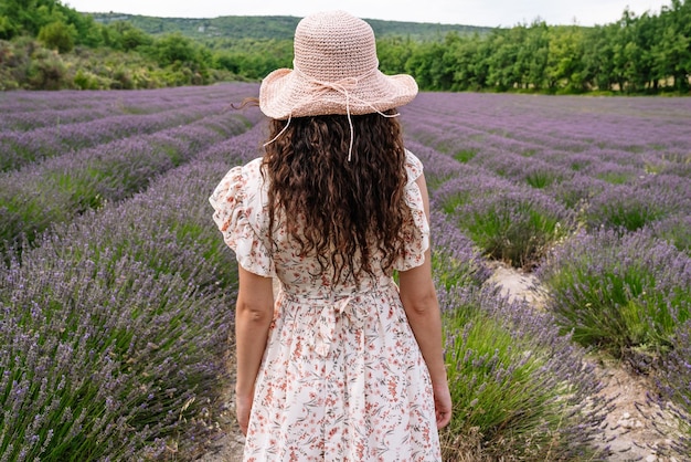 Mujer con sombrero de verano frente a un campo de lavanda