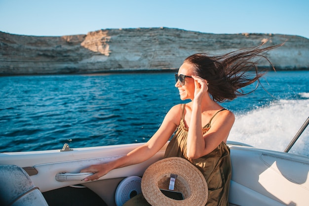 Mujer con sombrero y vestido navegando en barco en mar abierto claro