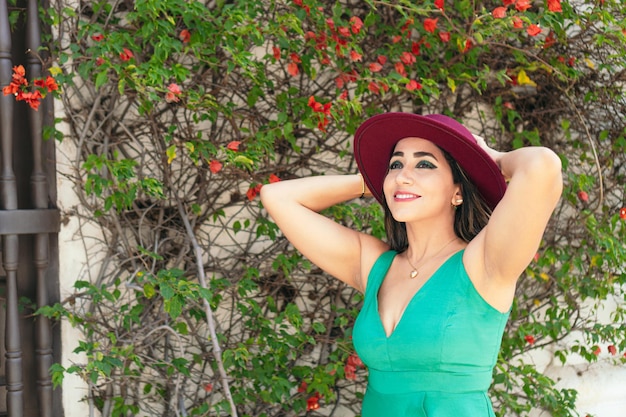 Mujer con sombrero y vestido, de pie en la calle.